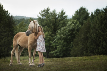 A young girl with a palomino pony in a field. 