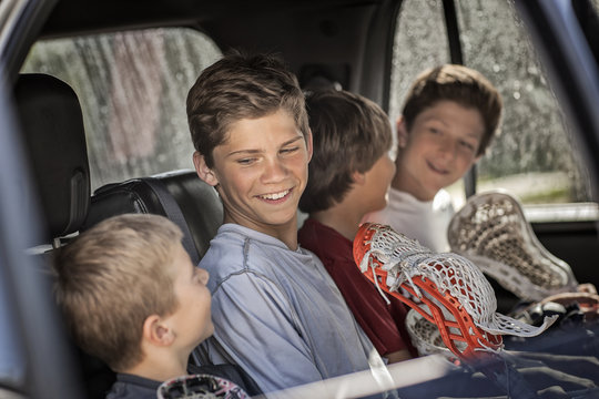Four boys sitting in car with lacrosse sticks
