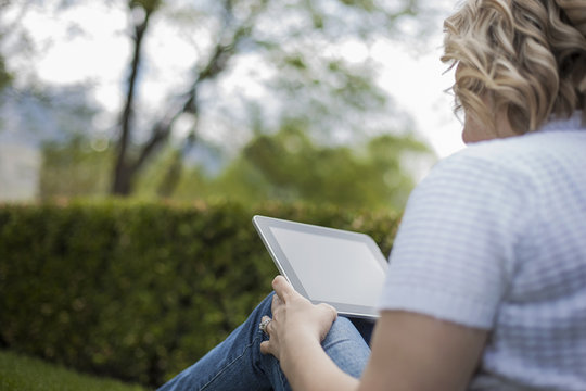 A young woman reading using a handheld electronic device, or e reader.