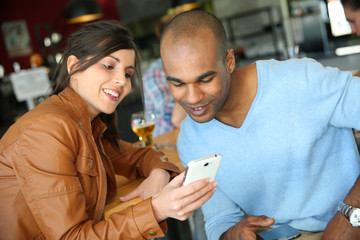 Young people in coffee shop using smartphones