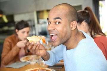 Young man having eating pizza slice