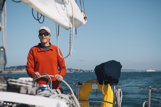 Middle aged man steering sailboat on Puget Sound, Washington, USA