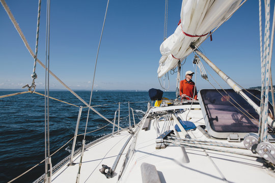 Middle aged man steering sailboat on Puget Sound, Washington, USA