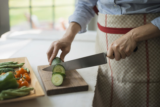 A  woman slicing organic vegetables. Cucumbers. 