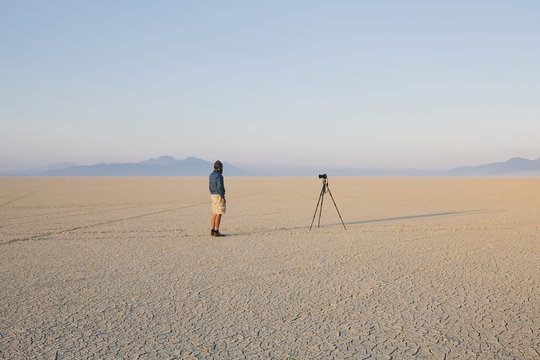Man with camera and tripod on the flat saltpan or playa of Black Rock desert, Nevada.