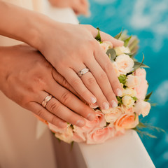 Obraz na płótnie Canvas Wedding rings with bouquet near the sea