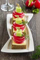 Appetizer of black bread with radish and cheese.