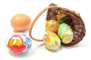 Colorful Easter eggs in overturned wicker basket and fresh egg