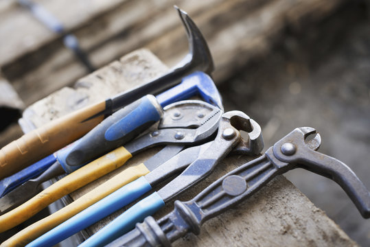 A reclaimed lumber workshop. A range of pliers and chisels on a plank of wood.