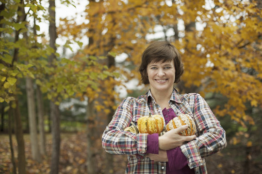 Organic farm. A woman holding an armful of large squash vegetables.