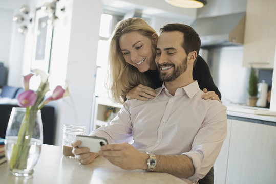 Couple at home looking at pictures on smartphone