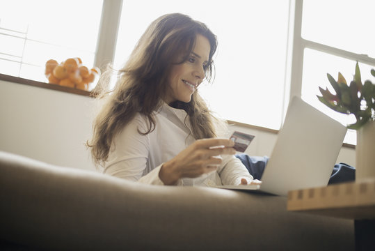 Woman on-line shopping on laptop on sofa with credit card