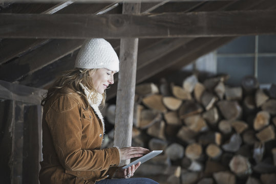 An organic farm in upstate New York, in winter. A woman sitting in an outbuilding using a digital tablet.