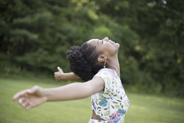A young woman in a summer dress with her arms outstretched, celebrating freedom.
