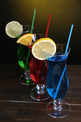 Glasses of cocktails on table on dark yellow background