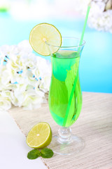 Glass of cocktail on table on light blue background