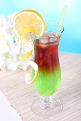 Glass of cocktail on table on light blue background