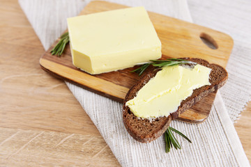 Slice of rye bread with butter on wooden cutting board
