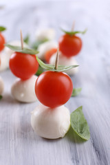 Tasty mozzarella cheese with basil and tomatoes, on wooden