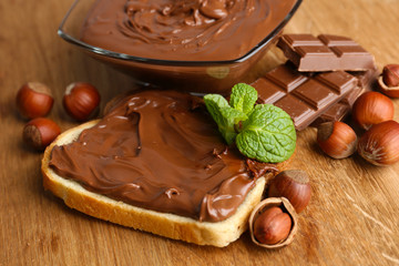 Bread with sweet chocolate hazelnut spread on wooden background