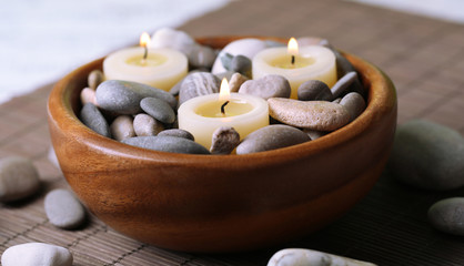 Composition with spa stones, candles on bamboo mat background
