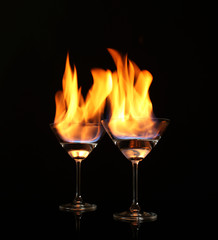 Glasses with burning alcohol on black background