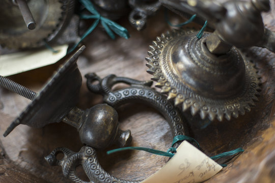 An antique store with a display of objects and furniture from the past. Chased metal decorated objects, door knocker and light fitting.
