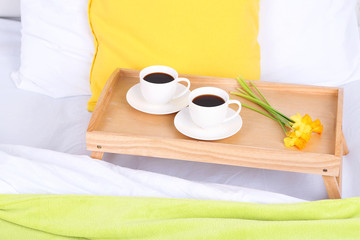 Cups of coffee on comfortable soft bed with pillows