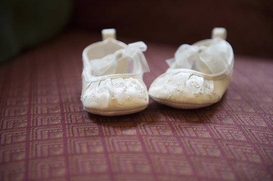 A pair of cream-coloured embroidered satin Christening boots with lace ribbon bows.