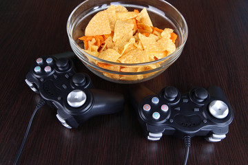 Black game controllers and bowl with snacks © Africa Studio