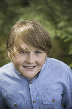 A boy in a denim button down shirt looking up at the camera. 
