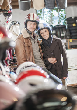 handsome couple choosing a trendy motorcycle's helmet in a speci