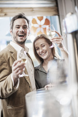 handsome couple toasting in a bar looking at camera