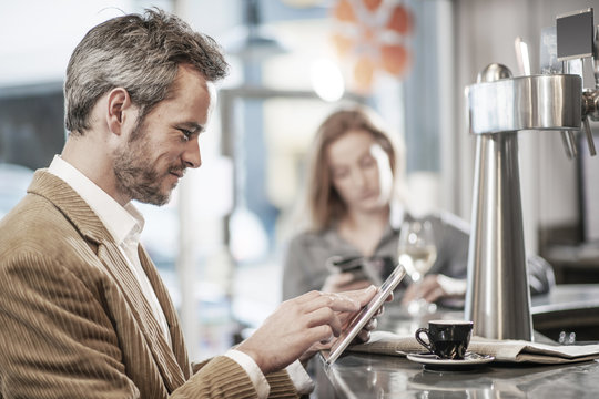 handsome man sitting in a bar and using a digital tablet - Powered by Adobe
