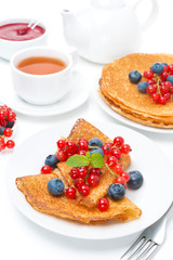 Breakfast with pancakes, fresh berries, jam and black tea