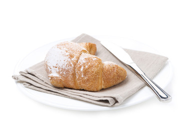 croissant and a knife on a white plate, isolated