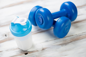 Shaker with protein and dumbbells, horizontal shot