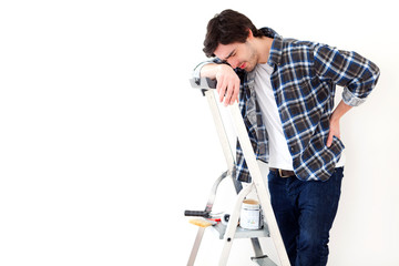 Young man suffering while working on a stepladder