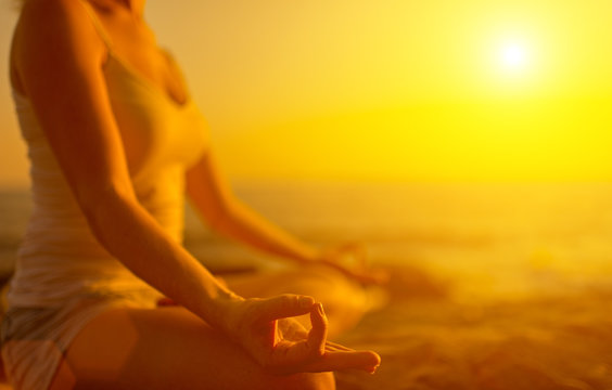 hand of  woman meditating in a yoga pose on beach at sunset