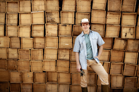 Farmer standing in front of stack of wooden boxes