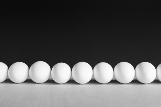 Row of white, free range, organic eggs, black background