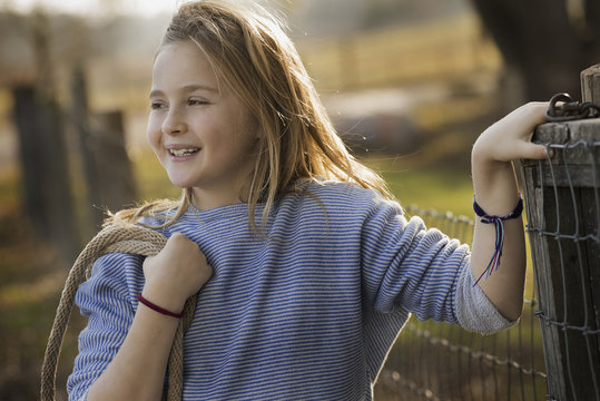 A young girl by a paddock fence.