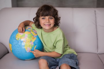 Portrait of a happy kid with globe in living room