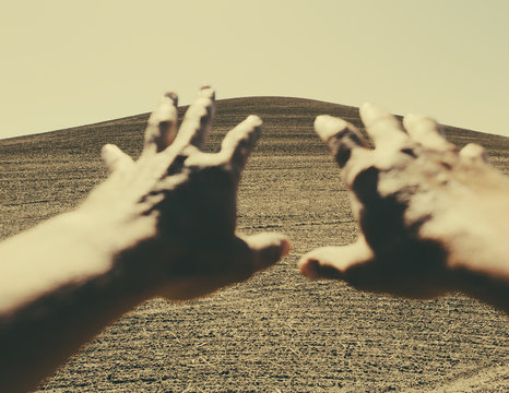 Hands extending reaching out towards ploughed farmland, near Pullman, Washington, USA