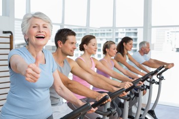 Fototapeta premium Woman gesturing thumbs up with class at spinning class