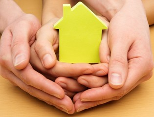 Man and woman hands holding conceptual paper house