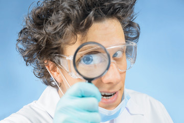 Mad doctor looks through a magnifying glass