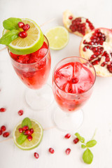 Two glasses with red pomgranate champagne, lime and mint.