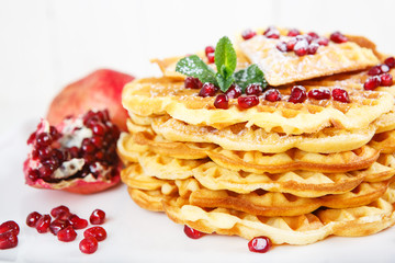 Crisp golden fresh baked waffle topped with strawberries on whit