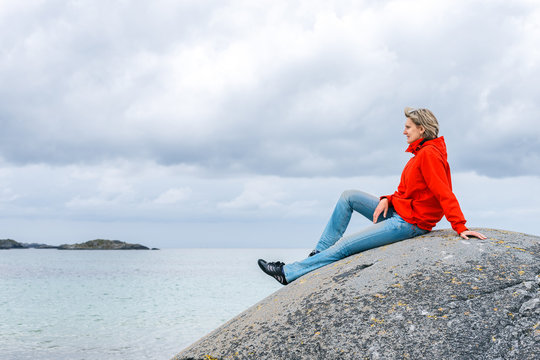 Woman sitting on stone and enjoying sea view